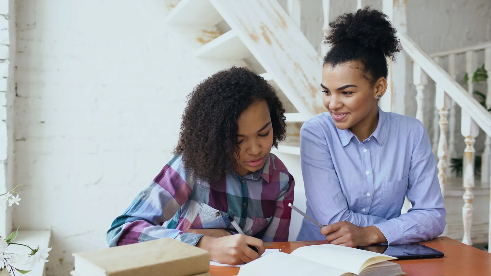 A parent helping a teenager with homework at the kitchen table
